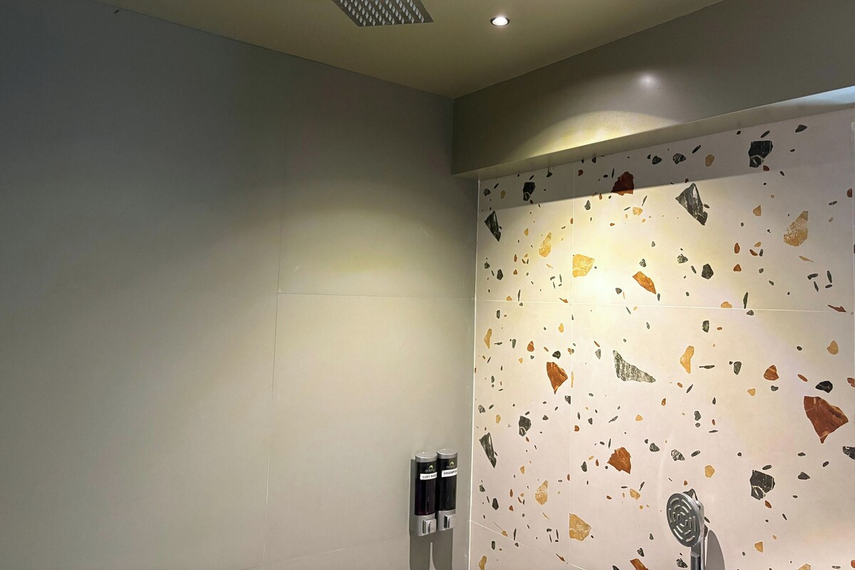 Ein Badezimmer mit Dusche, einer Wand mit Terrazzo-Boden und einer Decke mit Einbuchtungslampen.