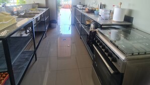 A modern kitchen with stainless steel appliances, wooden cabinets, and a large window providing natural light. - FBK Guest House  (Addis Ababa)
