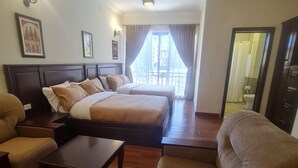 A hotel room with two beds, a sofa, a coffee table, and a view of the outside. - FBK Guest House  (Addis Ababa)