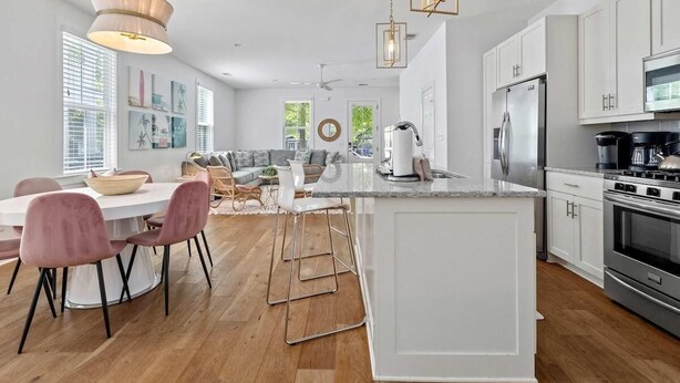 A modern kitchen with white cabinets, a stainless steel refrigerator, and a large island with bar stools.