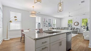 A modern kitchen with a central island, white cabinetry, and pendant lighting.
