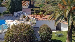 A residential area with a swimming pool, palm trees, and a view of the sea.