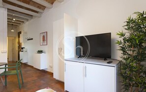 Relax in a cozy space with a flat-screen TV, comfortable chair, and a potted plant.