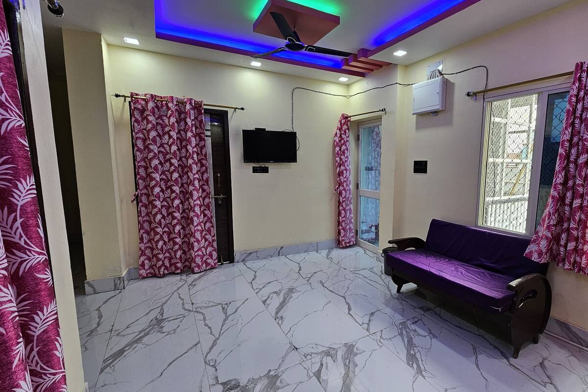 Una habitación con piso de mármol, un sofá púrpura y cortinas estampadas.