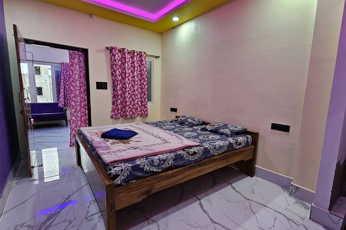 Un dormitorio con una cama, un banco y una puerta que da a otra habitación.