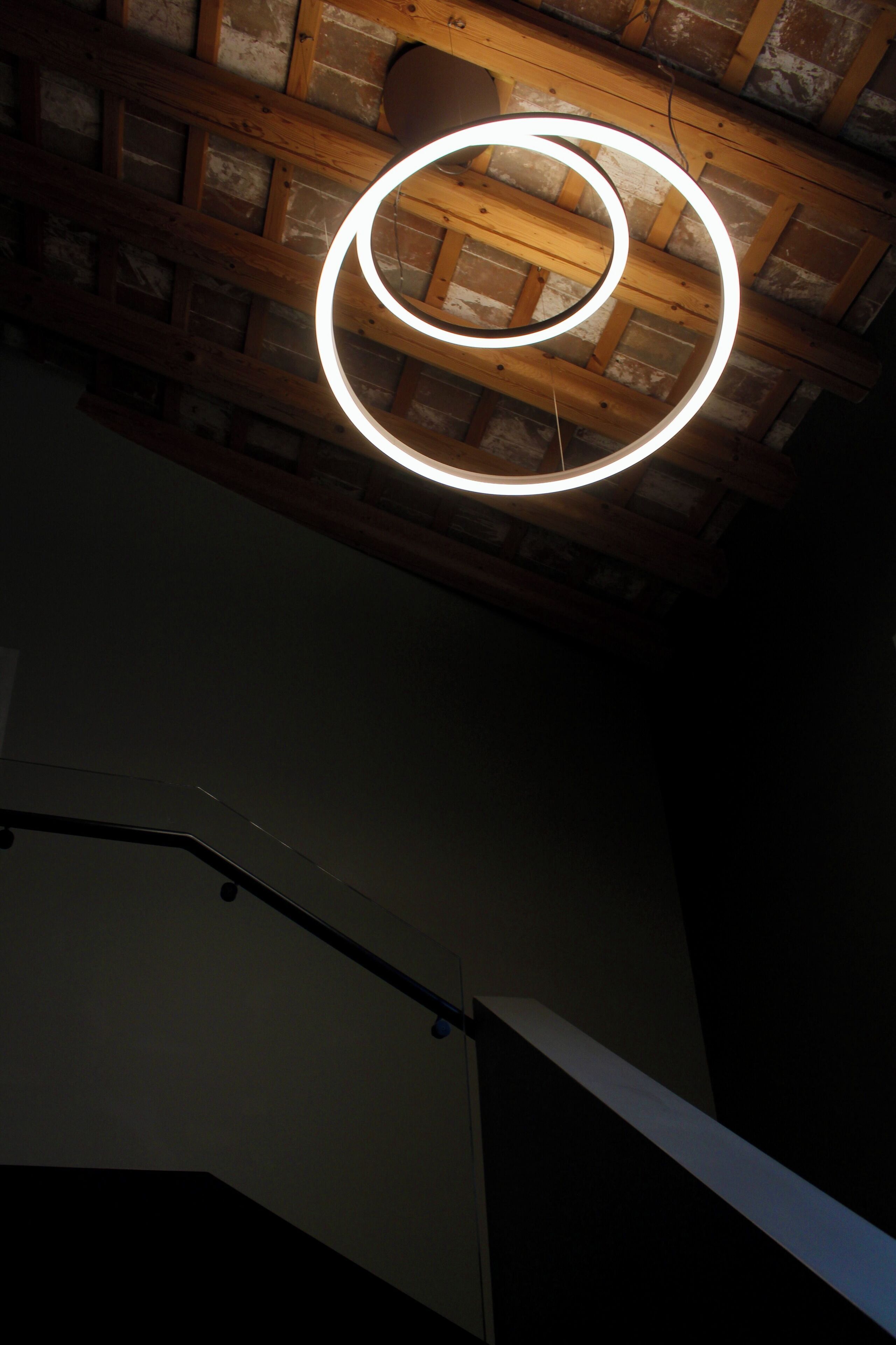 A spiral light fixture on a wooden ceiling with exposed beams.