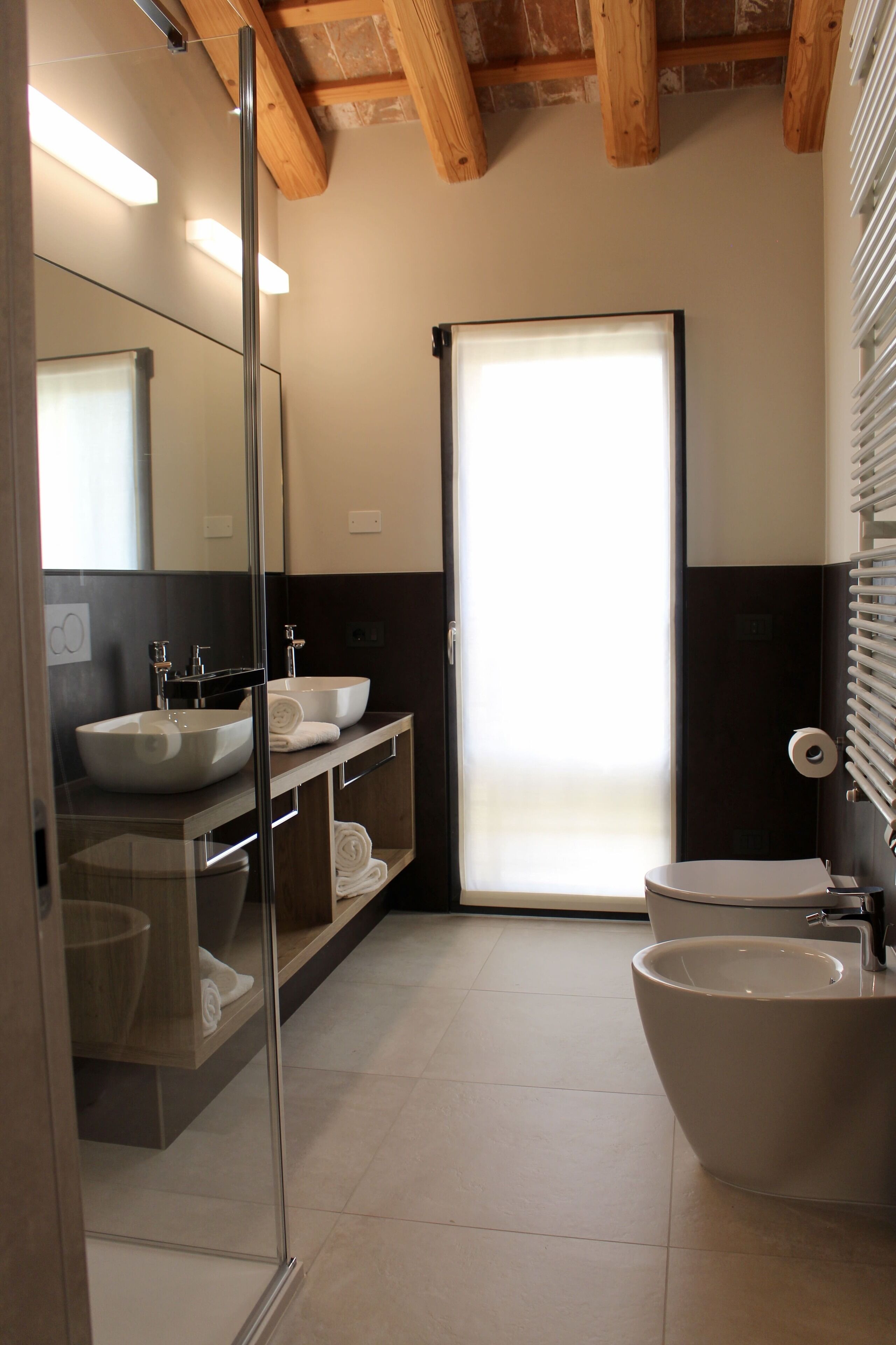 A modern bathroom with a glass shower enclosure, two sinks, and a toilet.