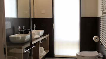 A modern bathroom with a glass shower enclosure, two sinks, and a toilet.