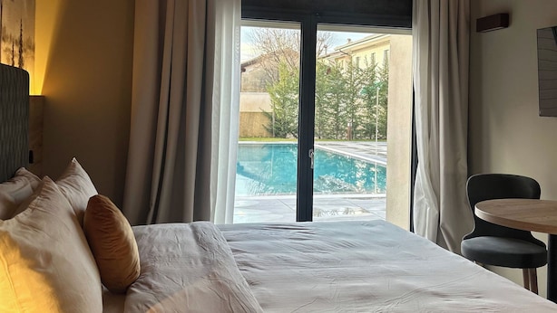 A hotel room with a bed, a view of a swimming pool, and a dining area. - Ida Boutique Hotel (Maser)
