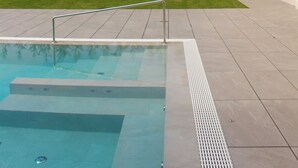 A swimming pool with a clear view of a building with arches and a hillside in the background. - Ida Boutique Hotel (Maser)