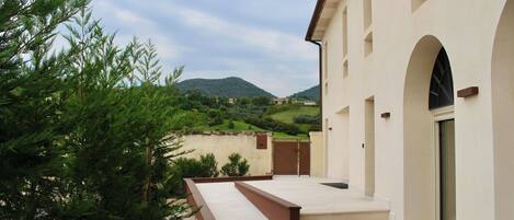 A building with a covered outdoor area, a staircase, and a view of green hills in the background.