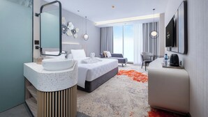 A modern hotel room with a large bed, a sitting area, a TV, and a bathroom with a sink and mirror. - Wahid Prime Hotel Salatiga (Salatiga)