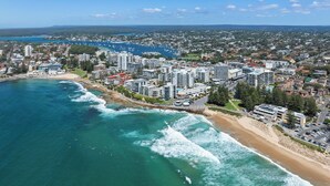 A coastal cityscape with high-rise buildings, a beach, and a marina.