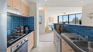A modern kitchen with blue tiles, stainless steel appliances, and wooden cabinets.