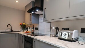 A modern kitchen with a marble countertop, a toaster, a coffee maker, and a sink. - Apt 2 @ Hunter's Quay (Bridlington)