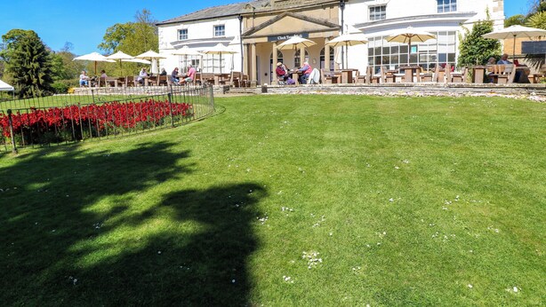 A building with a clock tower, outdoor seating, and a well-maintained lawn. - Apt 2 @ Hunter's Quay (Bridlington)
