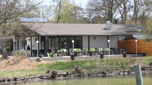 Een gebouw met een plat dak, grote ramen en terrasstoelen.