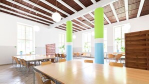 Een ruime eetruimte met hoge plafonds en zichtbare balken, met lange houten tafels en stoelen.