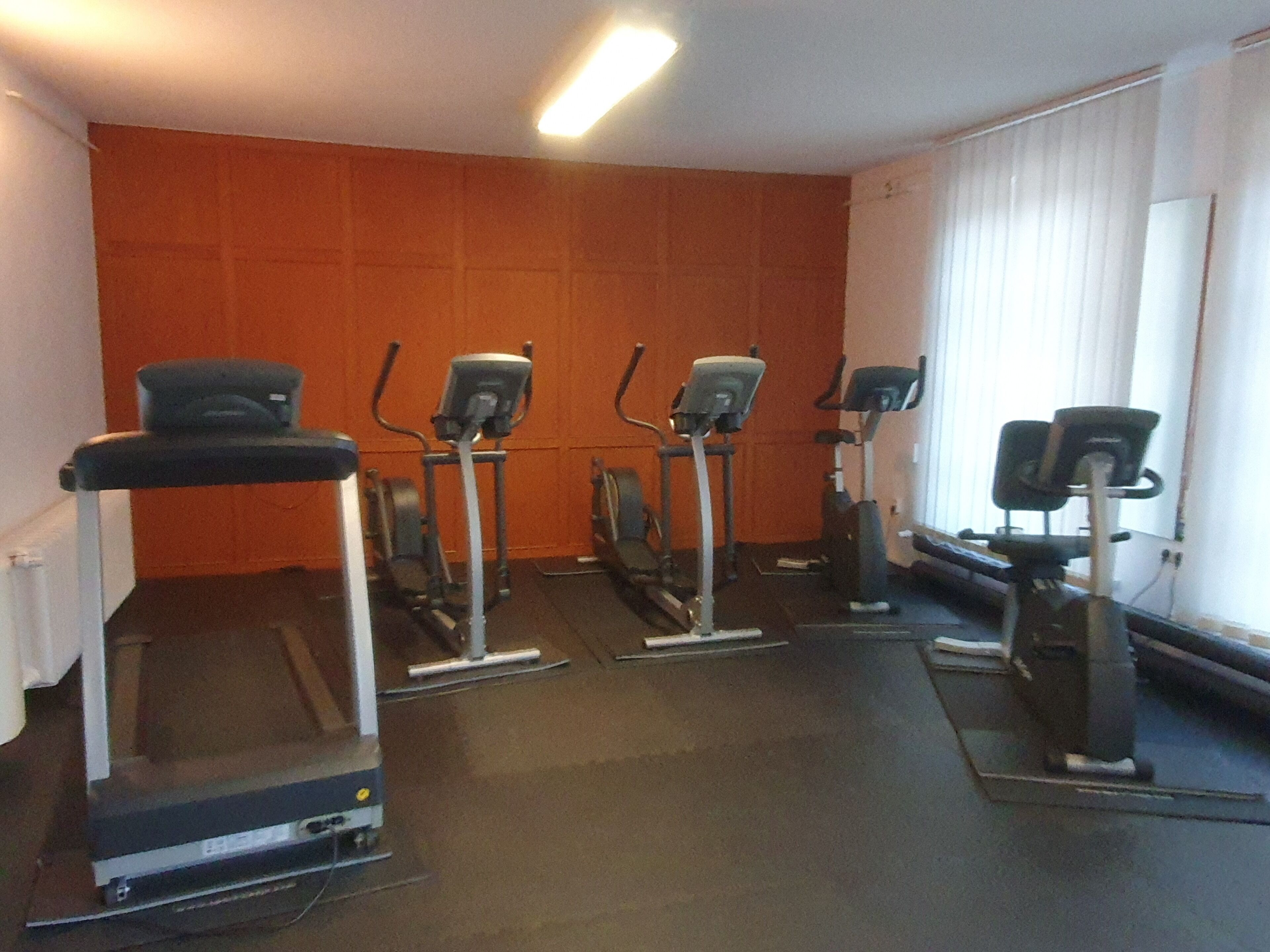Un gimnasio con cintas de correr, elípticas y bicicletas estáticas.