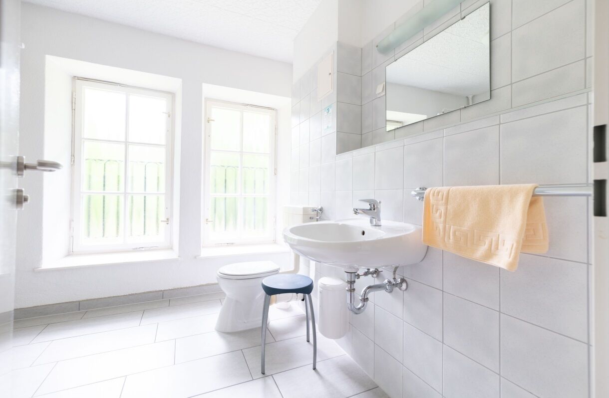 A bright bathroom with a white sink, toilet, and a window.