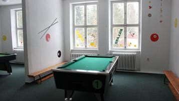 A pool table in a room with large windows, a radiator, and a bench.