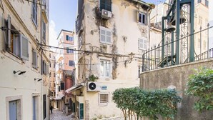A narrow cobblestone street flanked by historic buildings with balconies and shutters. - The Hidden Charm by Corfuescapes (Corfu)
