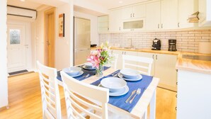 A modern kitchen with white cabinets, a stainless steel refrigerator, and a wooden countertop. - The Hidden Charm by Corfuescapes (Corfu)