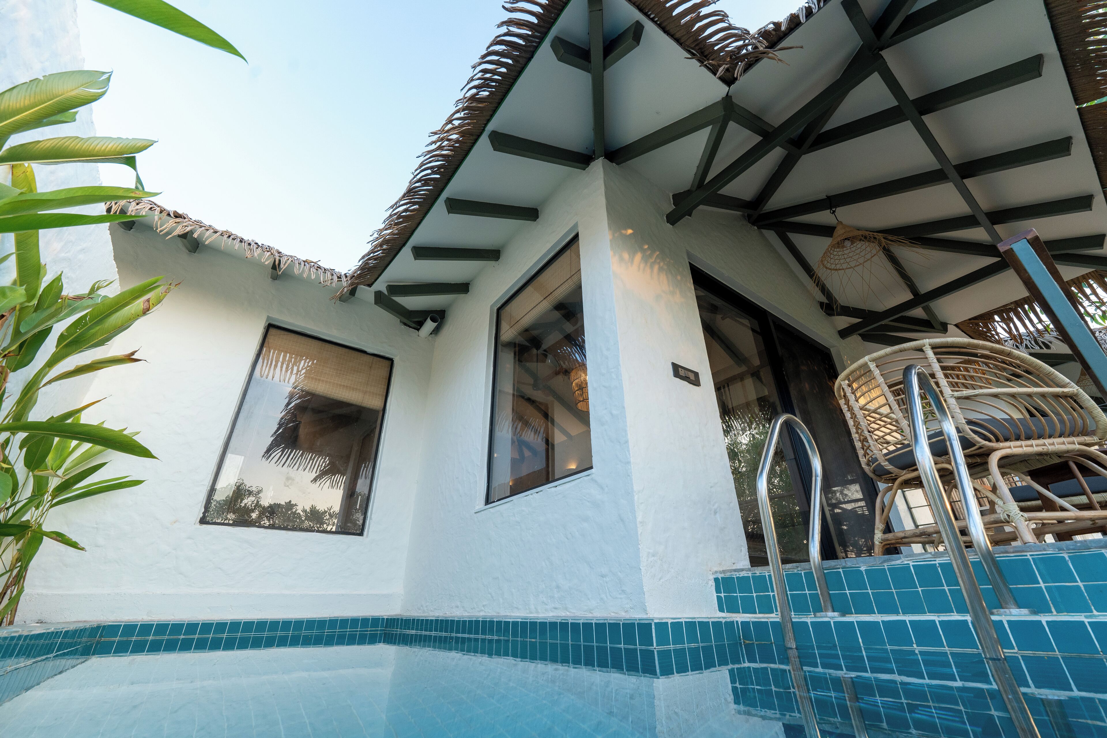 A pool area with a tiled floor, a wooden deck, and a thatched roof structure.