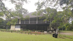 A two-story house with a balcony, surrounded by a well-maintained garden with various plants and flowers.