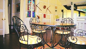 A dining area with a round table and four chairs, a patterned rug, and a wall with hanging decorations.