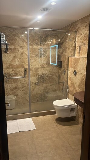 Un baño moderno con cabina de ducha de vidrio, inodoro y lavamanos.