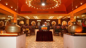 A restaurant with a central table, large pots, and a ceiling light fixture.