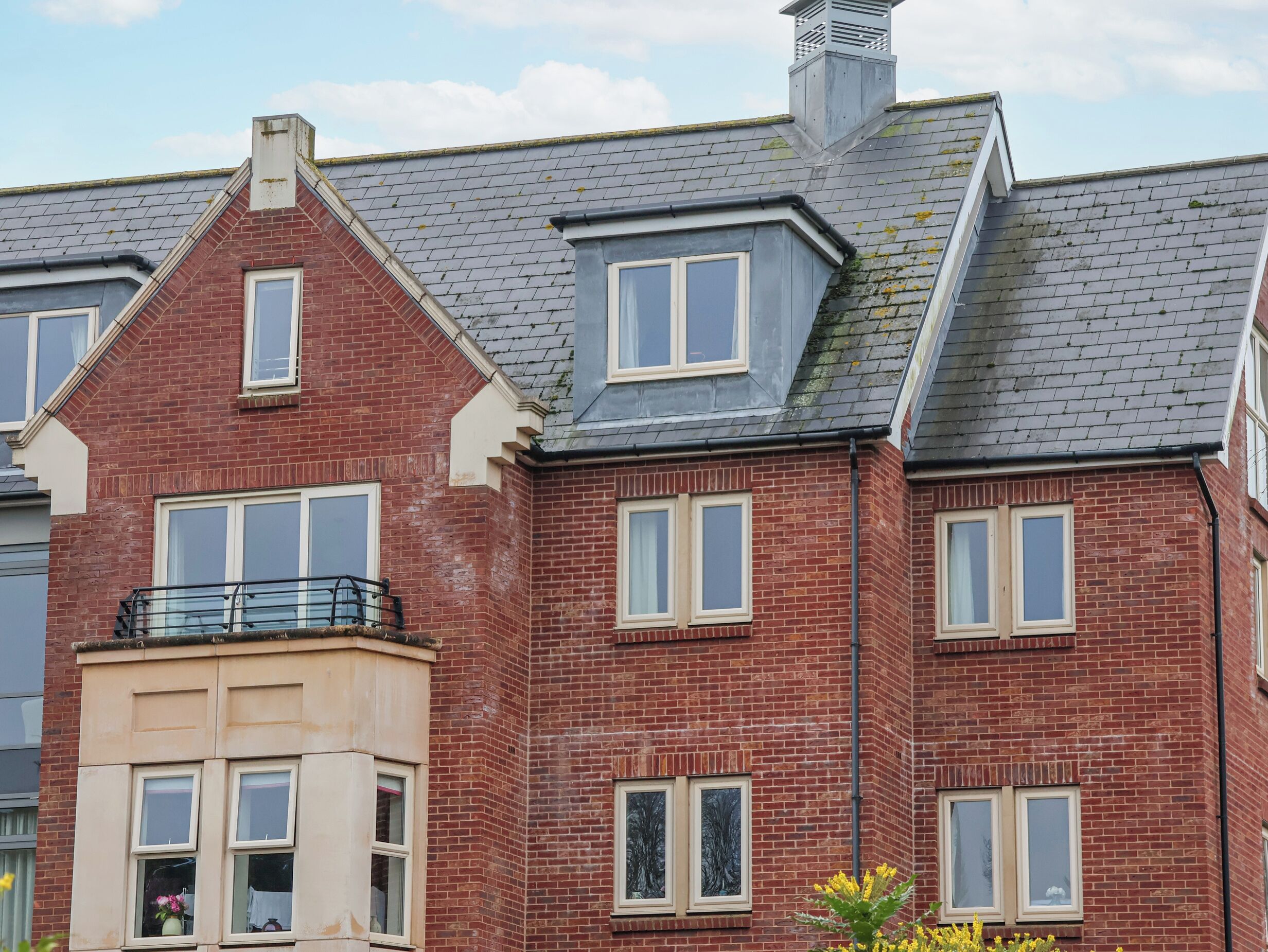 A red brick building with multiple windows and a balcony.