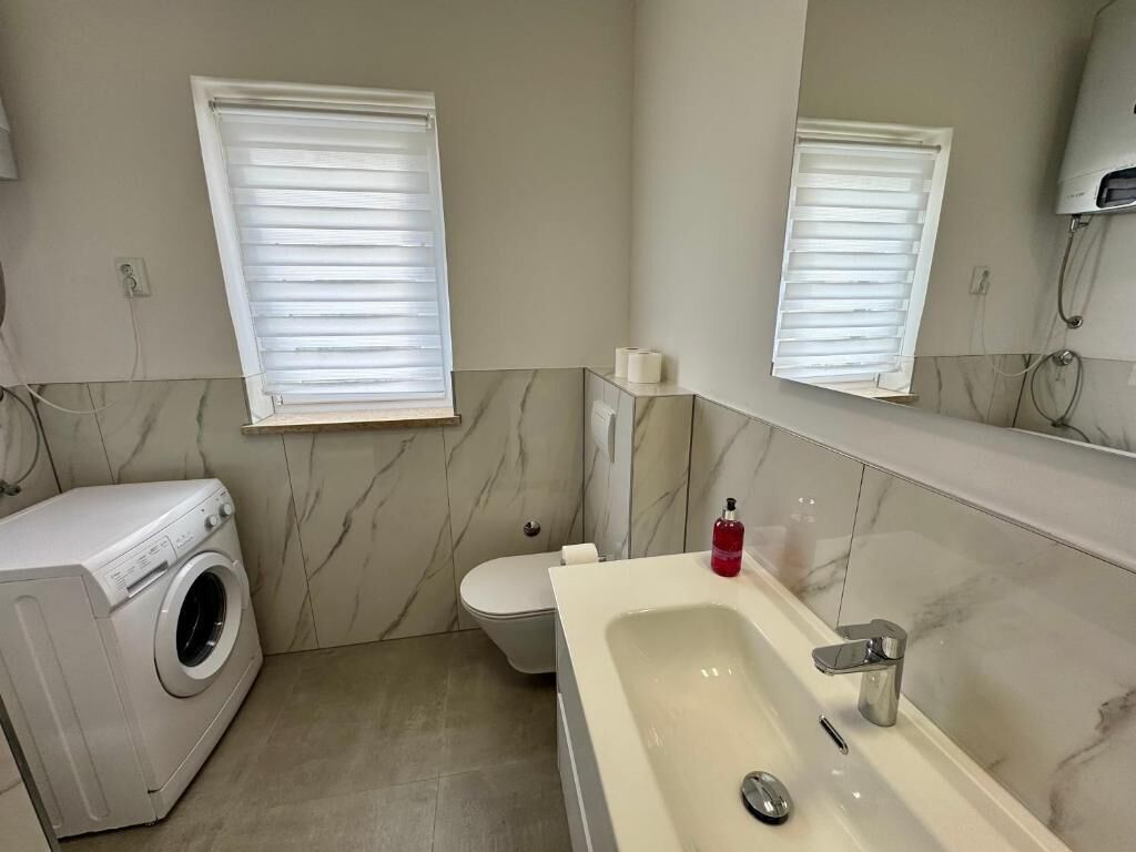 Een badkamer met een wasmachine, toilet en wastafel.