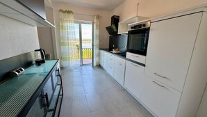 A modern kitchen with white cabinets, a black oven, and a green countertop. - Apartment Fruky (Jadranovo)