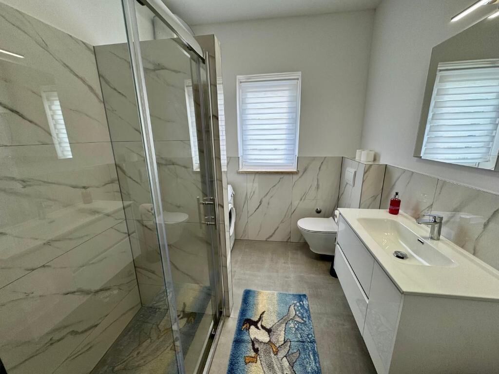 Une salle de bain moderne avec une douche à parois de verre, des toilettes et un lavabo avec un miroir.