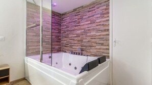 A modern bathroom with a glass-enclosed shower, a freestanding bathtub, and a textured wall. - Love Room with Jacuzzi, Le Saccard (Villeneuve-le-Roi)