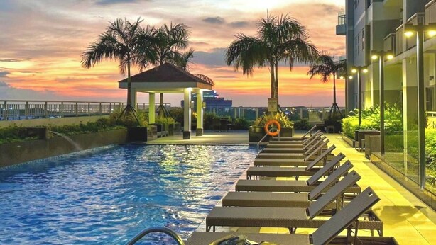 Une piscine avec des chaises longues, un kiosque, des palmiers et une vue imprenable sur le coucher de soleil.
