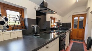 Une cuisine moderne avec un plan de travail noir, des appareils en acier inoxydable et une porte en bois.