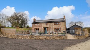 Une maison en pierre avec une façade en briques, une clôture en bois et une allée gravillonnée.