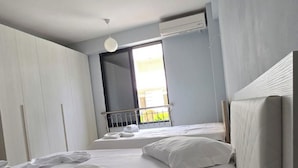 A hotel room with two beds, a large window, an air conditioning unit, and a balcony. - Tirent Apartment - Cozy Bedrooms Stay by Golem Beach. (Golem)