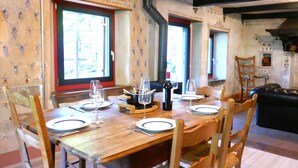 Un coin repas avec une table en bois dressée pour quatre personnes, entourée de chaises en bois.