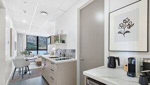 A modern kitchen with a built-in dishwasher, a dining area with a table and chairs, and a large window offering a view of the outdoors.