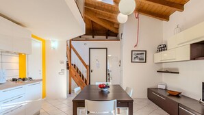 Una cocina moderna con armarios blancos, una mesa de comedor de madera y una escalera que sube a un nivel superior.