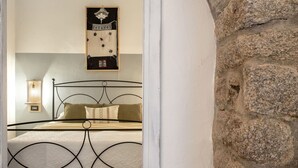 A bedroom with a metal bed frame, a wall-mounted artwork, and a stone wall. - Wonderful private villa for 6 people with WIFI, TV, patio and pets allowed (Aglientu)