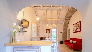 A spacious kitchen with a wooden counter, a red sofa, and a stone wall. - Wonderful private villa for 6 people with WIFI, TV, patio and pets allowed (Aglientu)