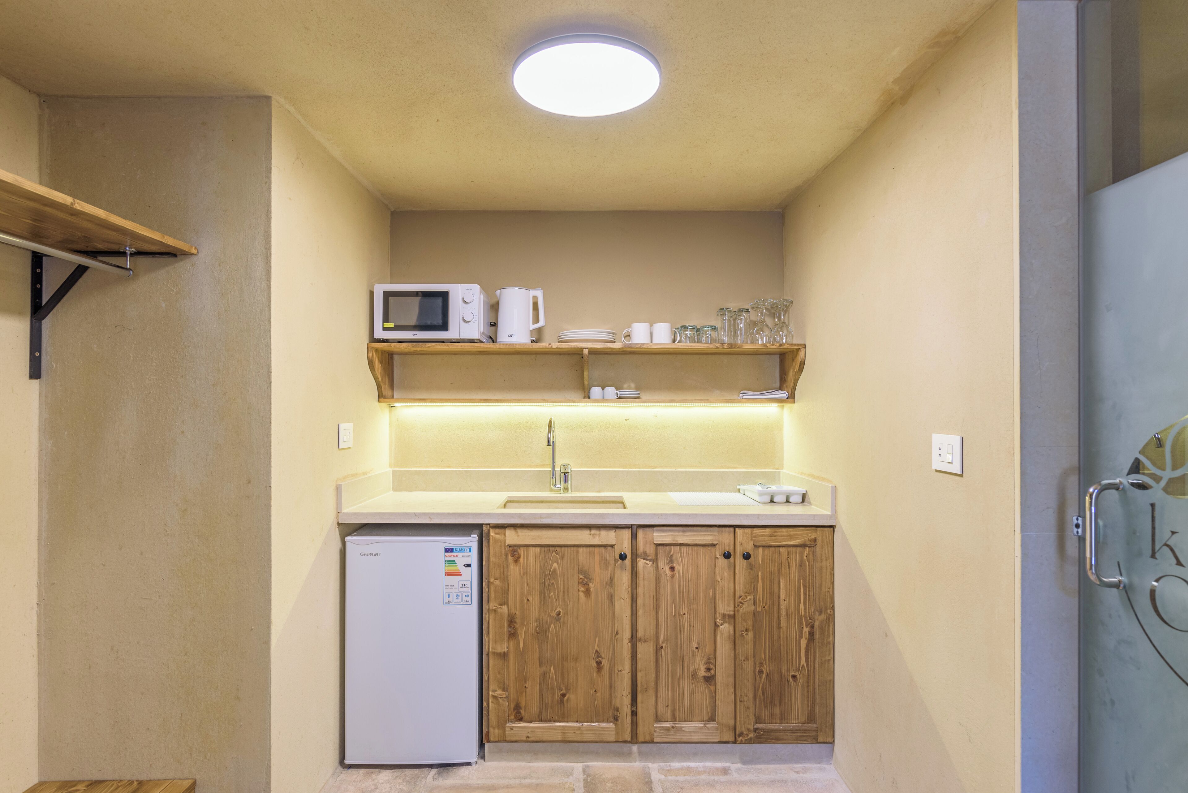 A compact kitchen with a built-in microwave, a sink, and wooden cabinets.