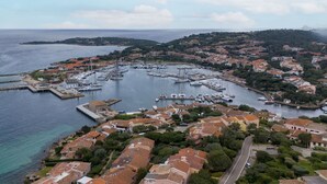 Un poble costaner amb un port esportiu, cases terrassades i una vista clara del mar.