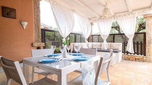 Terrassa exterior amb taula blanca preparada per dinar, envoltada de cadires blanques.