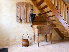 Cozy retreat with a wooden chest, table, and copper kettle, set against a backdrop of a wooden staircase.